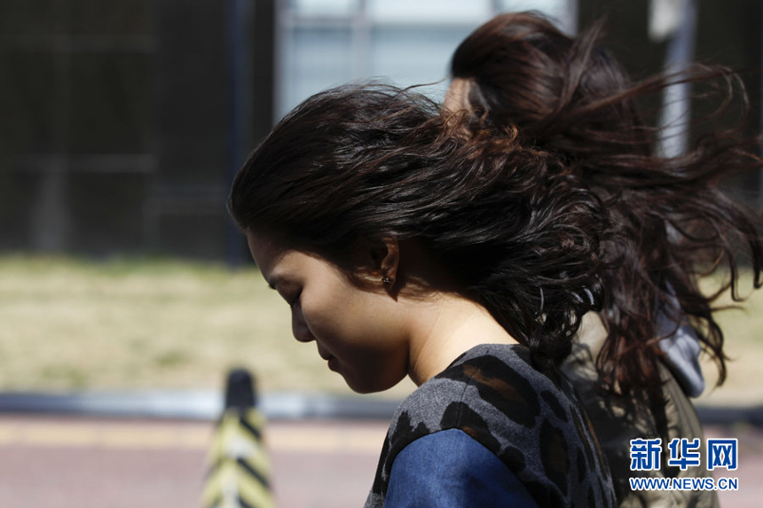 Two women walk against the gale in downtown Beijing, April 5. Meteorologists issue a strong wind warning early today. 