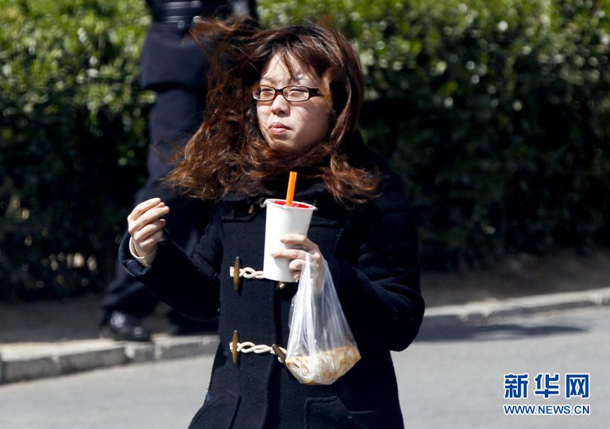 People walk against the gale in downtown Beijing, April 5. Meteorologists issue a strong wind warning early today. 