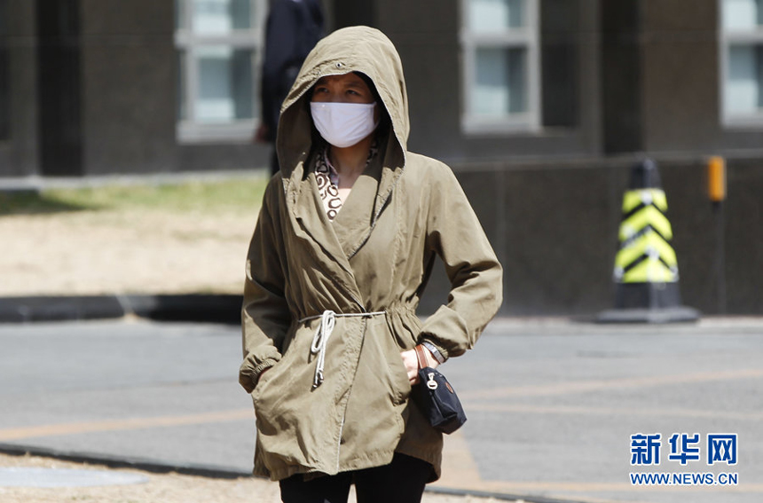 A woman walks against the gale in downtown Beijing, April 5. Meteorologists issue a strong wind warning early today. 