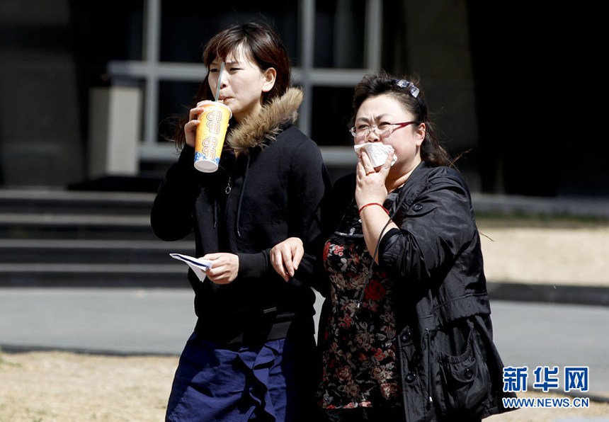 Two women walk against the gale in downtown Beijing, April 5. Meteorologists issue a strong wind warning early today. 