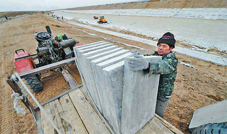 A worker unloads concrete slabs for the project aimed at diverting water from the Nenjiang River in the northeastern provinces of Heilongjiang and Jilin. [Xinhua] 