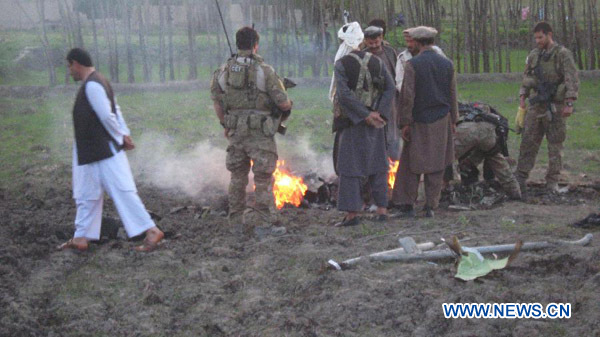 NATO troops and local Afghans investigate at the site where a NATO drone crashed in Baghlan province, north Afghanistan, April 6, 2012. A NATO unmanned aerial vehicle crashed in northern Afghanistan on Friday, the NATO-led forces said in a press release. [Xinhua/Sahel]