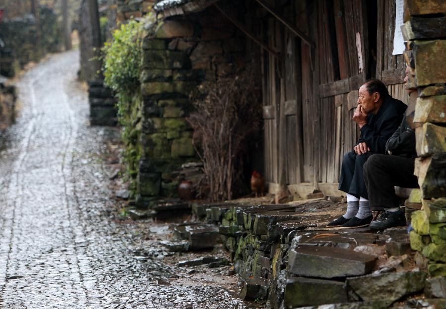 People rests beside a road at Xujiashan village in Ninghai county, southeast China's Zhejiang Province, April 9, 2012. As most of the houses and roads in Xujiashan village was built with the basalt, it is also known as the stone village.