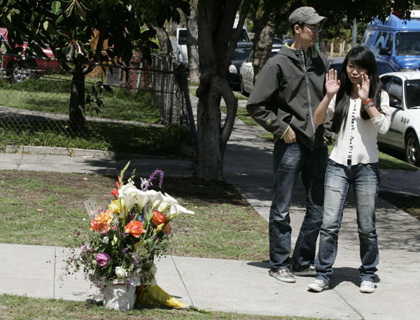 Ming Qu (L) and Ying Wu leave flowers at the scene where two international students from China were shot dead on Wednesday in a 'gang-infested' area near the University of Southern California in Los Angeles, California, April 11, 2012. [Agencies] 