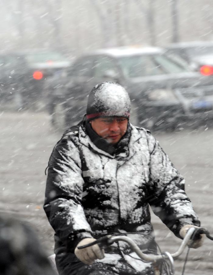 A citizen rides bicycle in snow in Harbin, capital of northeast China's Heilongjiang Province, April 12, 2012. A snowfall hit the city on Thursday. [Xinhua]