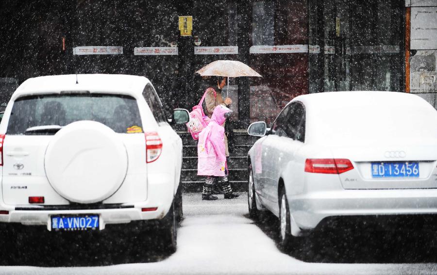 People walk in snow in Harbin, capital of northeast China's Heilongjiang Province, April 12, 2012. A snowfall hit the city on Thursday.