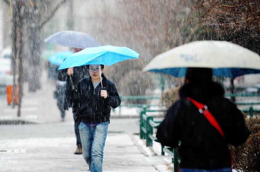 People walk in snow in Harbin, capital of northeast China's Heilongjiang Province, April 12, 2012. A snowfall hit the city on Thursday.