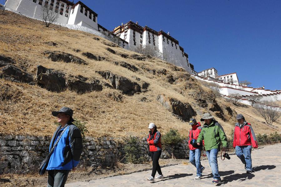 Tourists walk at the foot of the Potala Palace in Lhasa, southwest China's Tibet Autonomous Region, April 12, 2012. The Potala Palace will extend its opening hours during the rush season to meet tourists' demand, the palace's administration said recently. (Xinhua/Wen Tao) 