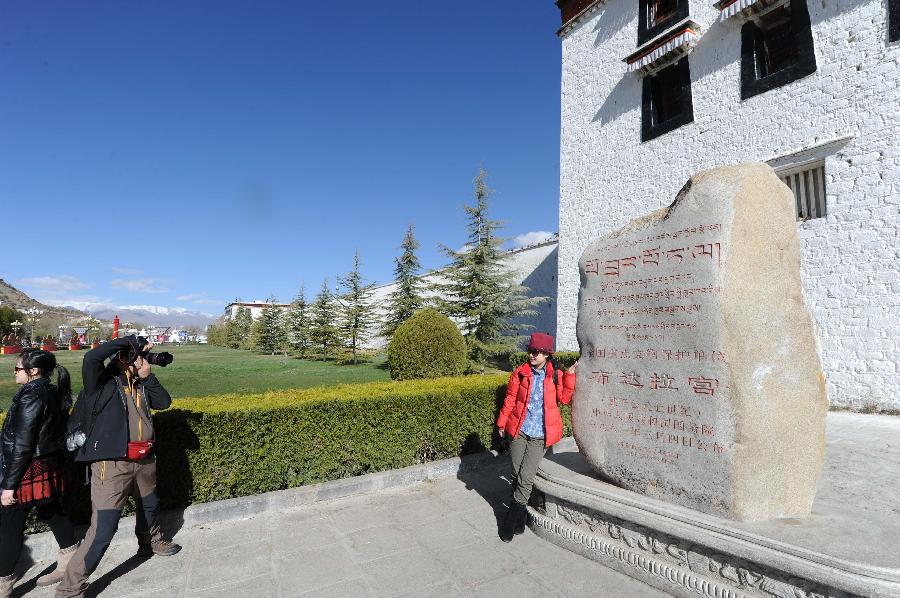 Tourists take photos at the Potala Palace in Lhasa, southwest China's Tibet Autonomous Region, April 12, 2012. The Potala Palace will extend its opening hours during the rush season to meet tourists' demand, the palace's administration said recently. (Xinhua/Wen Tao) 