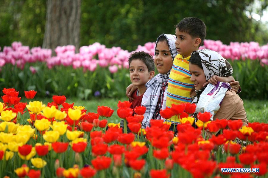 Iranian children are seen near flowers at a park in Tehran, Iran, on April 12, 2012. Spring flowers blossom here as the temperature keeps rising recently. (Xinhua/Ahmad Halabisaz) 