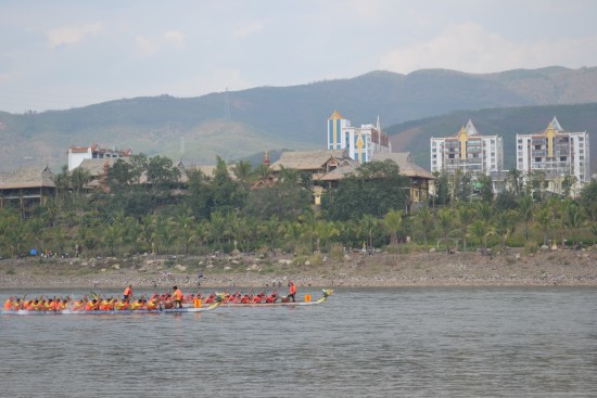 Boat number four appears to be edging boat one in a 24-man dragon boat race in Jinghong City, Yunnan Province to mark the start of the Dai New Year holiday, Apr. 13. Newly built housing and resorts line the Mekong riverfront.