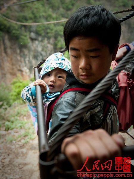 Children cross the rift by taking the strop ropeway. (chinapic.people.com.cn)