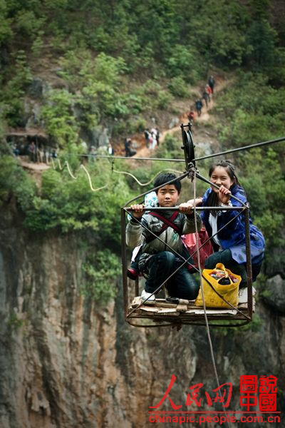 Children cross the rift by taking the strop ropeway. (chinapic.people.com.cn)