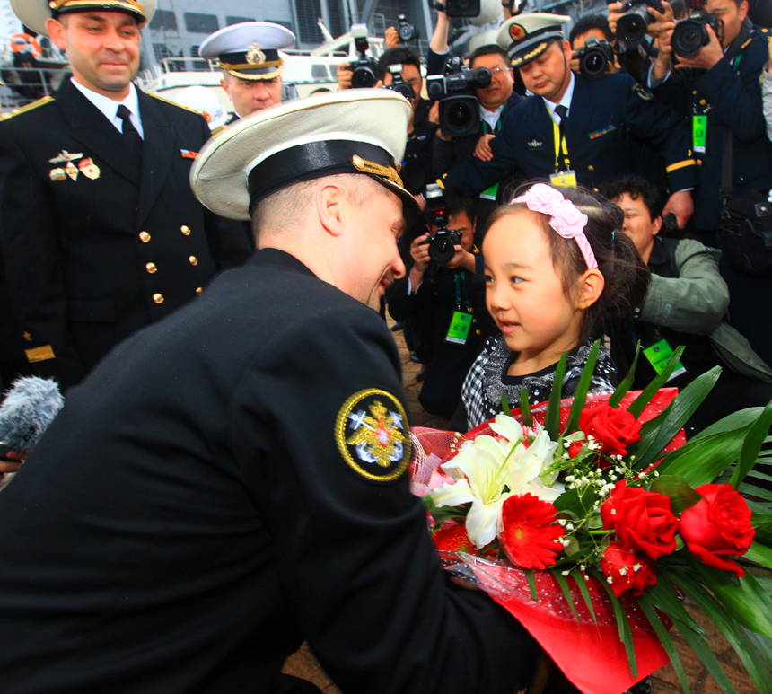 A Russian naval task force arrived at a naval base in Qingdao of east China's Shandong Province on Saturday for a joint exercise with the Chinese navy next week. In the photo, a Chinese girl presents flowers to Russian naval commander. [Xinhua photo]