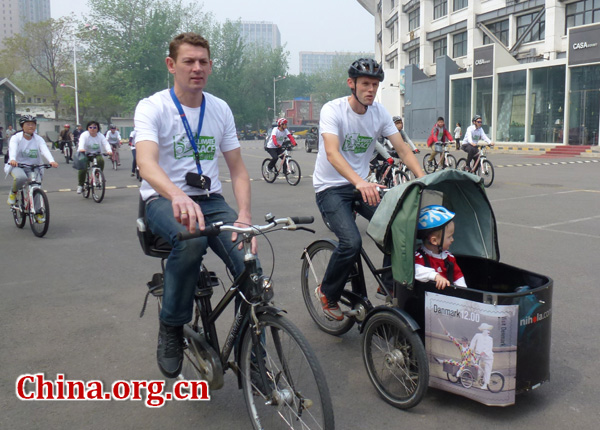 Some foreign participators ride bike with their baby in the front carrier.