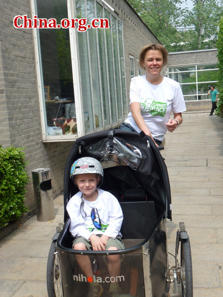 A foreign participant rides her bike with her son in the front carrier.