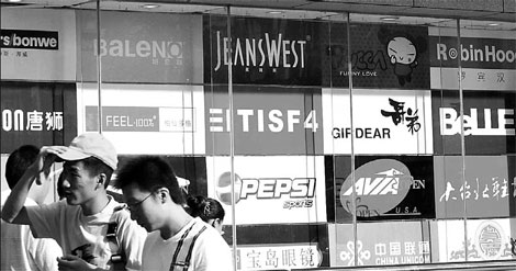 People walking past an advertising board of logos in Nanjing, Jiangsu province. Despite the de facto control of the market by foreign firms, local advertising companies have an edge in understanding local culture. [File photo]