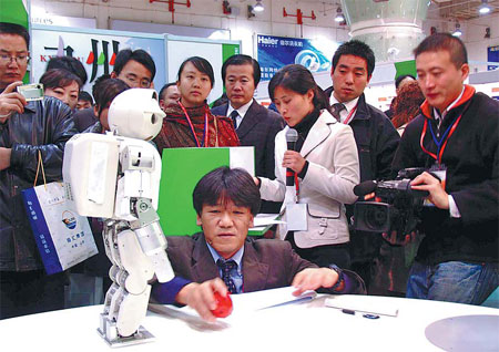 Visitors to a trade fair involving businesses from China, Japan and South Korea look at a robot in Qingdao, Shandong province. Experts say the time is ripe for the three countries to start talks on establishing a free trade area. [China Daily]