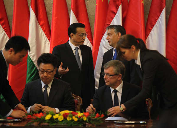 Vice-Premier Li Keqiang (back left) talks with Hungarian Prime Minister Viktor Orban during the signing of agreements at the parliament building in Budapest on Tuesday. [Fu Jing/China Daily]