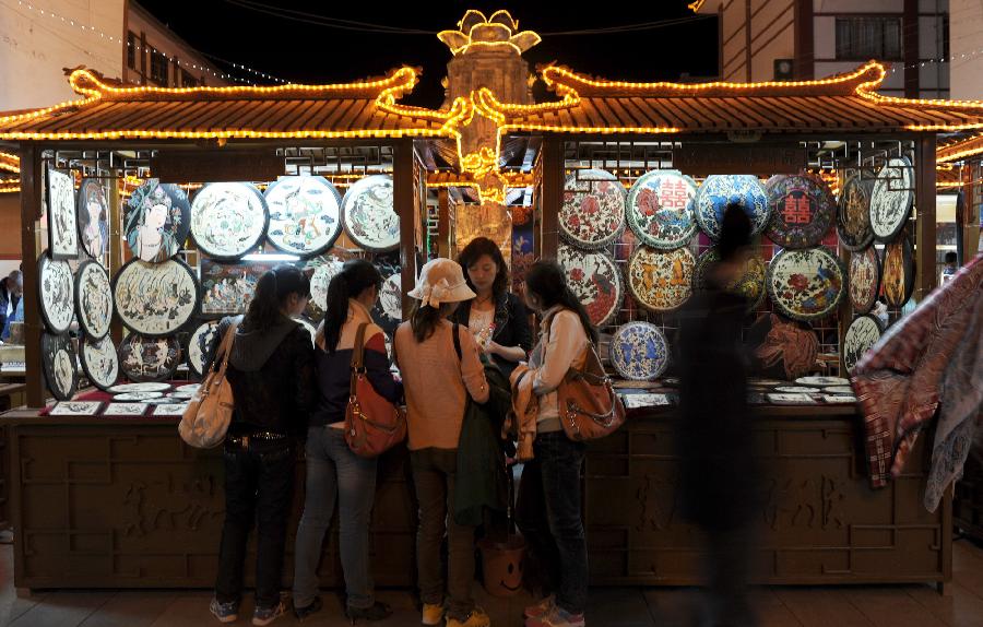 Tourists buy woodcuttings at the Shazhou Market in Dunhuang, northwest China's Gansu Province, April 30, 2012. As tourism industry booms in Dunhuang, more than 500 folk artists have been attracted to develop their businesses in Dunhuang, which is well known for its Mogao Caves (Caves of 1,000 Buddhas), Crescent Lake and Mingsha Mountain. (Xinhua/Gao Jianjun) 