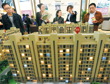 Visitors look at models of a housing project at the Nanjing (Spring) Real Estate Trade Fair on April 12. Average home prices in 100 Chinese cities fell 0.71 percent year-on-year in April, the first such drop since June 2011. [China Daily]