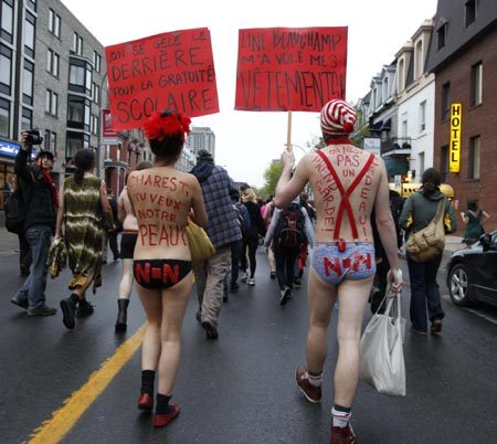 Students march against tuition hikes during a protest in downtown Montreal, Quebec, May 3, 2012. Words on (L) reads &apos;You want our skin.&apos; The placard reads &apos;We are freezing our asses off for free school.&apos; [Photo/Agencies]