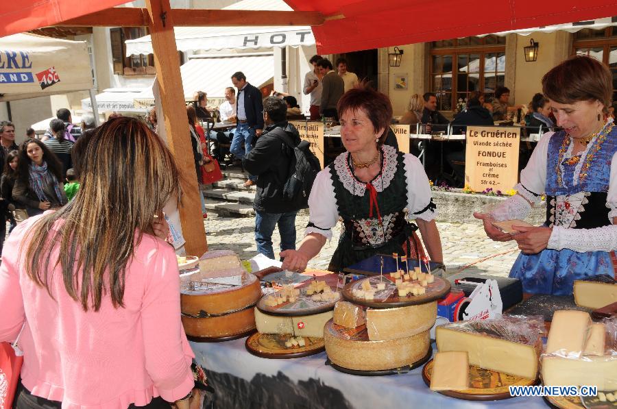 Local residents introduces Gruyere cheese to a tourist during the cheese festival in Gruyere, Switzerland, May 6, 2012. [Xinhua/Yang Jingde]