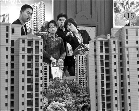 A saleswoman shows building models at the Suzhou Spring House Purchasing Festival in April. More than 60 percent of the property developers whose shares trade on the country's A-share market reported lower profits or losses in the first quarter. [China Daily]
