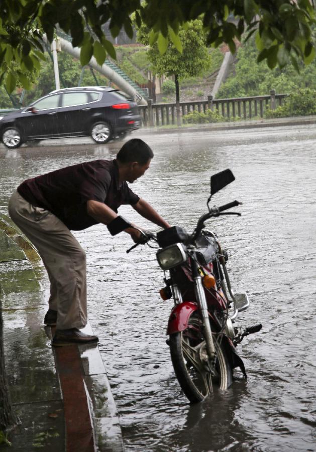  A citizen pushes his motorcycle on a waterlogged road in Loudi, central China's Hunan Province, May 9, 2012. 