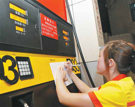 A worker copies a gasoline price list at a gas station in Guiyang, Guizhou province. Gasoline and diesel prices will be reduced by 330 yuan and 310 yuan per ton respectively from Thursday. [China Daily]