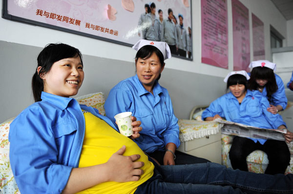 Song Qianqian, who is eight months pregnant, chats with one of her colleagues in a lounge specially designed for female workers in a textile company in Qingdao, East China’s Shandong province, in April.[Xinhua]