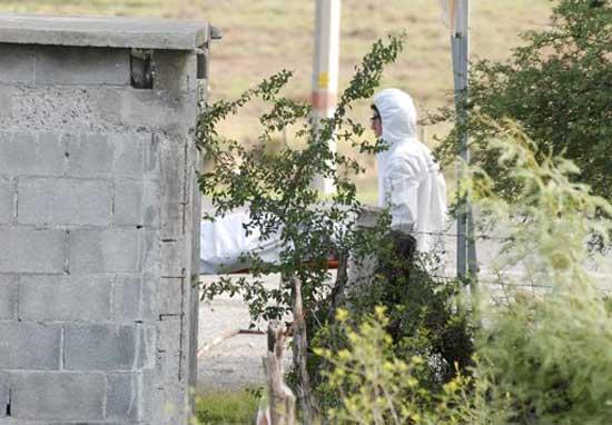 Forensic technicians remove a body from a crime scene in the municipality of Cadereyta May 13, 2012.