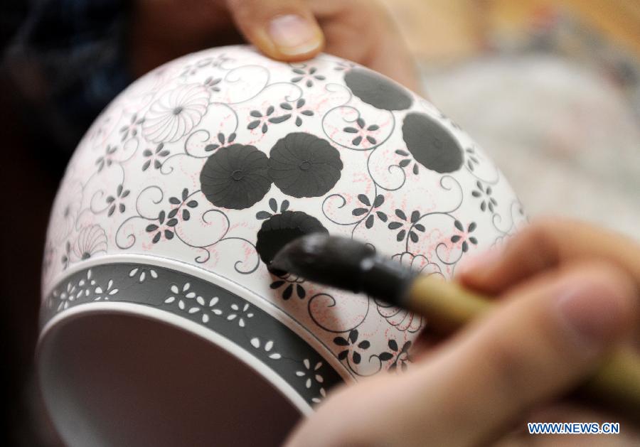 An artist paints a porcelain adobe for firing at a procelain workshop in Jingdezhen City, east China's Jiangxi Province, Dec. 21, 2011. 