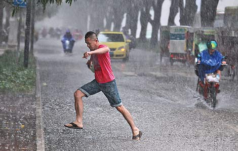 A man crosses a flooded street in heavy rain in Nanning, the Guangxi Zhuang autonomous region, on Monday. [China Daily]