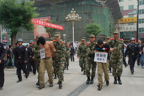 Two criminal suspects are escorted on a perp walk in Luonan county, Northwest China's Shaanxi province, May 13, 2012. [Photo/163.com]