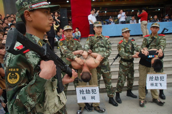 Two criminal suspects are escorted on a perp walk at a square in Luonan county, Northwest China's Shaanxi province, May 13, 2012. [Photo/163.com] 