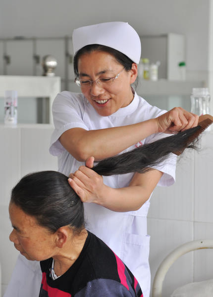  A nurse combs the hair of a new patient at the Mental Health Center of Zouping, Shandong province, on Friday. [ Photo/  China Daily ]