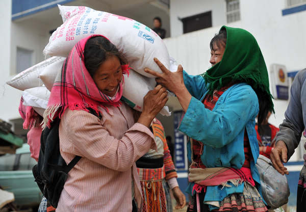 A woman carrying rice provided by the Red Cross Society in Guangxi in April 2010. The society gave 30 metric tons of rice to low-income villagers in Longlin county. [ Photo / Xinhua ] 