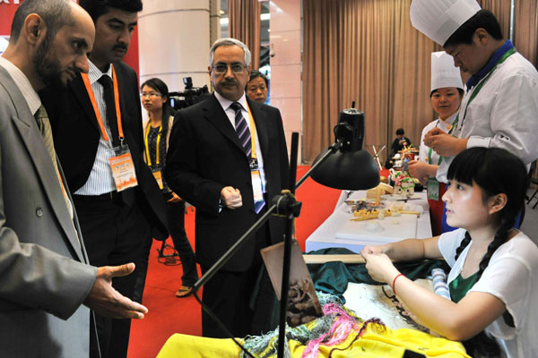 Visitors talk to a student majoring in embroidery at the Third International Congress on Technical and Vocational Education and Training in Shanghai on Monday.[ Photo / China Daily ]