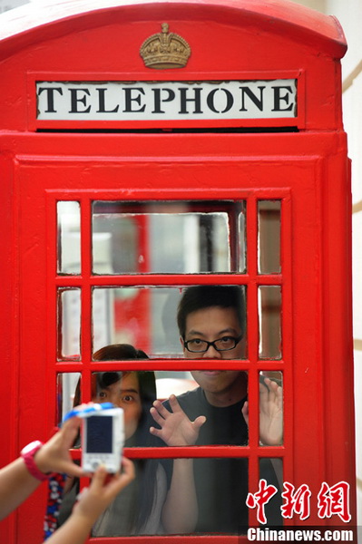 Two tourists pose for photo inside a 'London style telephone booth' in the Water Cube in Beijing on May 16. (CNS Photo / Hou Yu)