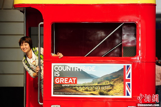 A tourist poses for photo in front of a 'London double-deck bus' in the Water Cube in Beijing on May 16. [CNS Photo / Hou Yu]