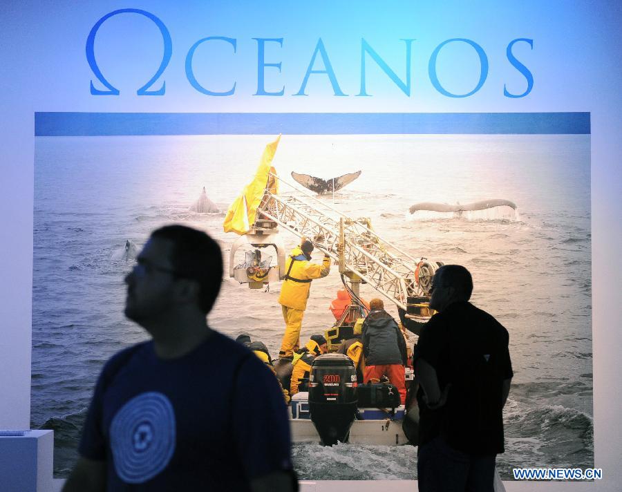 A man (R) looks at photos on display at an exhibition of the documentary film 'Oceans' that opens in Rio de Janeiro, Brazil, May 17, 2012. (Xinhua/Weng Xinyang) 