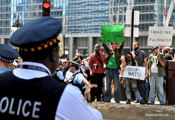 Protestors participate in a rally as police officers stand nearby in Chicago, the United States, on May 18, 2012. Over 2,000 people rallied in downtown Chicago Friday to protest against the policies of G8 and NATO.