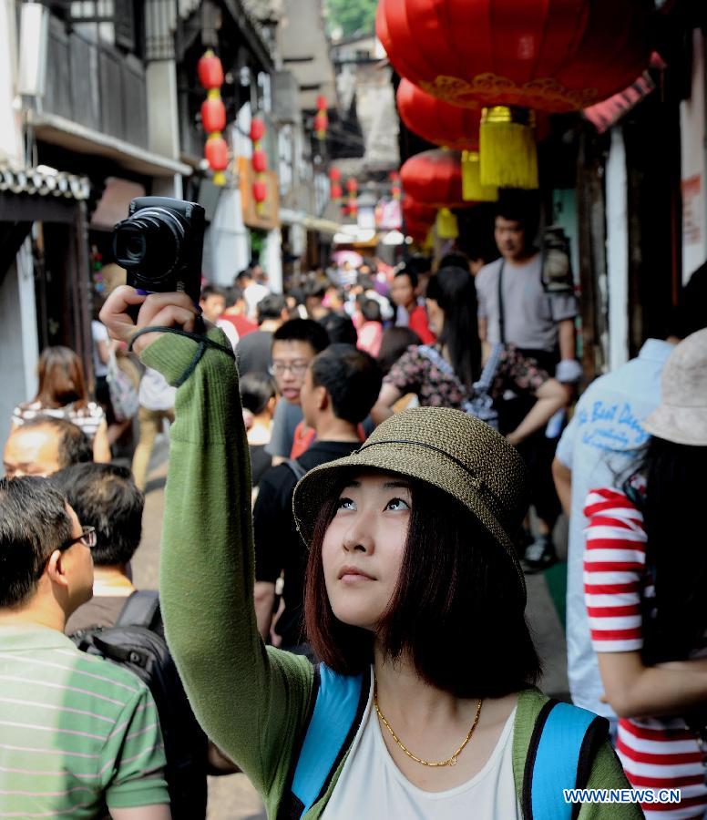 A visitor takes photos of the ancient Ciqikou Town in southwest China's Chongqing Municipality, May 19, 2012. Scenic spots across the country see lots of visitors on Saturday, the second China Tourism Day. (Xinhua/Li Jian) 