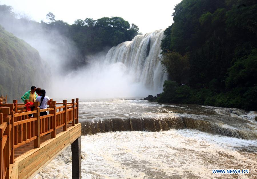 Visitors enjoy the sight of the Huangguoshu Waterfall in southwest China's Guizhou Province, May 19, 2012. Scenic spots across the country see lots of visitors on Saturday, the second China Tourism Day. (Xinhua/Gu Shangtai) 