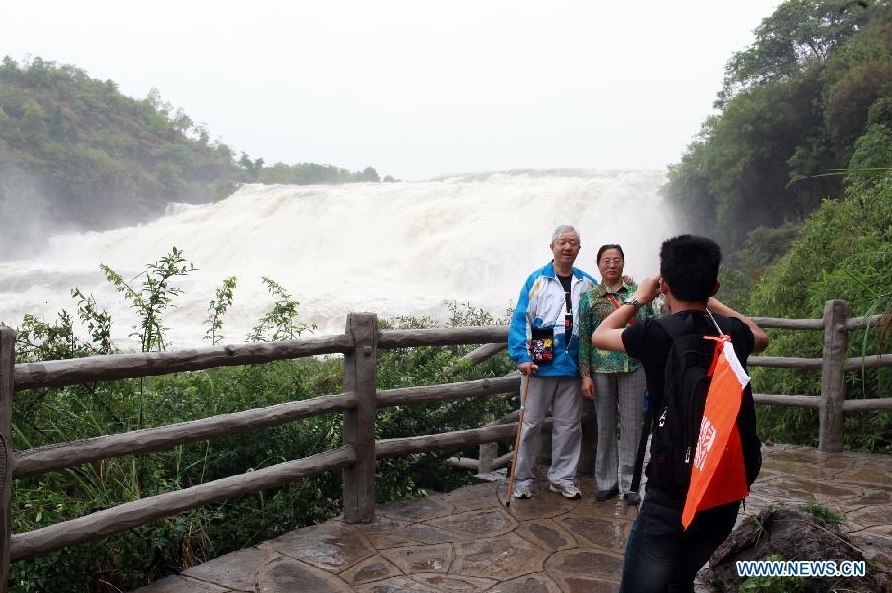 Visitors pose for photos at the scenic spot of Doupotang Waterfall, the upper reaches of the well-known Huangguoshu Waterfall in southwest China's Guizhou Province, May 19, 2012. Scenic spots across the country see lots of visitors on Saturday, the second China Tourism Day. [Xinhua/Gu Shangtai]