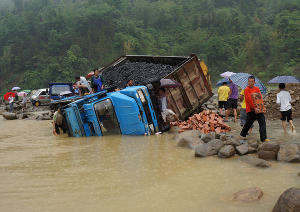 A truck sits on its side in water at the highway S312 between Wangmo and Anshun in Guizhou province on May 21,after torrential rains hit Wangmo and destroyed part of the road. [China Daily]