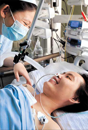 Zhang Lili, a teacher in northeastern China's Heilongjiang Province who was run over by a bus trying to save two pupils, smiles to a nurse Monday, May 21, 2012. 