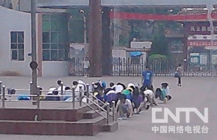 An online photo shows students kneeling in front of a national flag. [Internet photo]