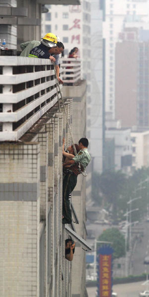 Firefighters rescue a woman who attempted to jump from a 12th-floor window in Dongguan, Guangdong province on April 18. The woman was suffering from family problems. [Photo / for China Daily ]